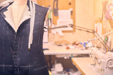 Semi-ready jacket on mannequin with measuring tape across neck. Suit tailoring in process of...