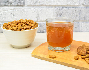 Crispy appetizing crackers in a white plate, a glass with a cold drink, on a wooden kitchen board, against a brick wall background. Side view.Copy space. Selective focus.