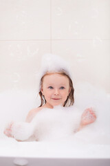 baby bathes playing in the bathtub with foam