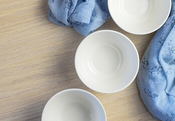 White clean empty plates on a wooden table with a blue napkin. Top view.