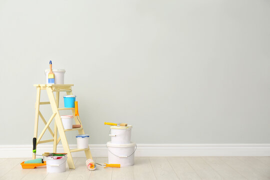 Decorator's kit of tools and paints near light wall indoors. Space for text
