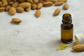 Almond essential oil in a small bottle and dropper on a light background