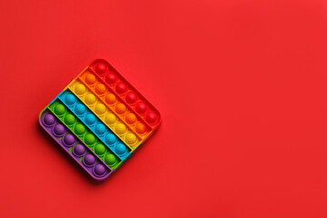 Rainbow pop it fidget toy on red background, top view. Space for text - obrazy, fototapety, plakaty