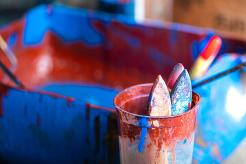 Set of used wooden painting brush in the glass with blurred background of color basket. Selective...
