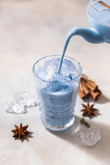Blue matcha latte in glass glass on light concrete background. Blue tea masala tea.
