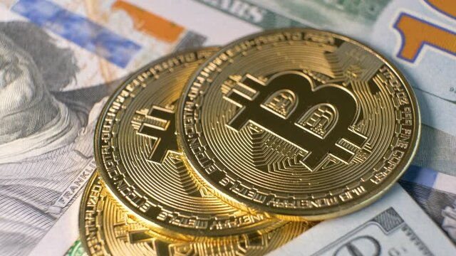 Close up of metal shiny bitcoin crypto currency coins on US dollar bills. Electronic decentralized money concept.