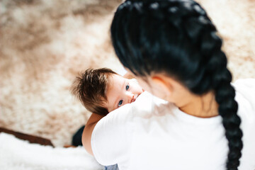 happy mom breast-feeds her newborn baby in a white bed