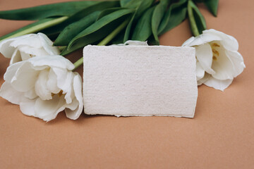 Blank card mockup on brown background with white tulips flowers.