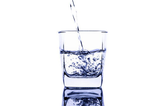Pour water into a clear glass with a splash of water. Isolated on white background