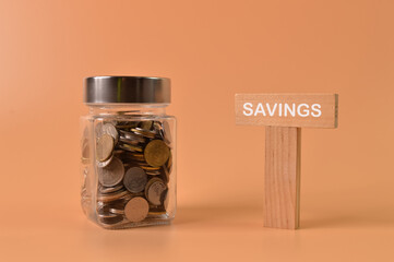 A lot of coins in glass money jar with text SAVINGS. Saving for investment concept.