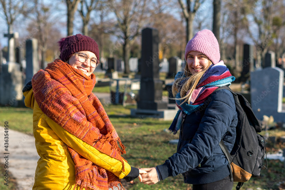 Wall mural Lesbian romantic couple holding hands in a cemetery