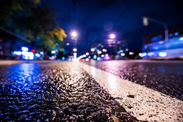 Night city after rain, the headlights of passing cars racing. Wide angle view of the level of the...