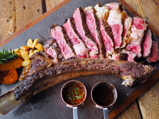 Top view beautifully sliced medium rare grilled giant huge large bone in Australian tomahawk beef...