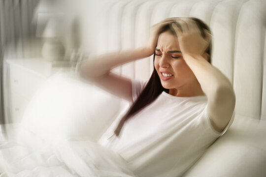 Young woman suffering from migraine in bed at home