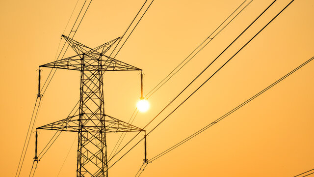 High power electricity pole silhouetted against the orange sky at dusk, Electric pole in India, with copy space