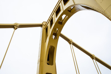 Structure of a self anchored suspension bridge seen from below painted yellow, horizontal aspect