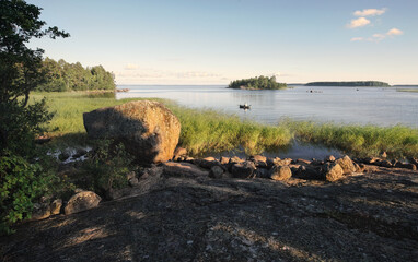 granite islands with stones and boulders, angler fishing in boat. Clean nordic nature in North Europe, Baltic sea, gulf of Finland