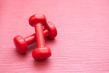 Red dumbbells set on pink background with copy space, sport and fitness concept 