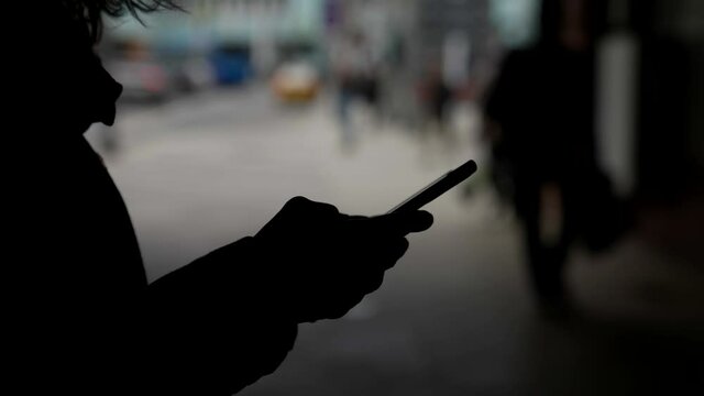 anonymous user of social nets, dark silhouette of person with smartphone in hands, sending message