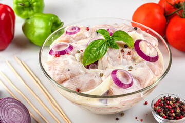 Raw chicken breast fillet marinated with mayonnaise or sour cream sauce, pepper, onion, basil in a...
