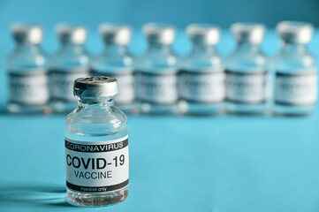 Coronavirus COVID-19 Vaccine Glass Bottle on blue surface with blue background at Thailand. Concept viruses spread throughout the world. Selective Focus.