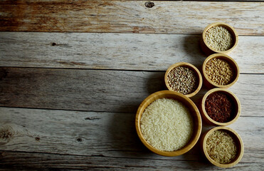 Fototapeta na wymiar Brown Glutinious Rice, Red Jasmine Rice, Oat Rice, Barley, Millet Rice, Brown Wheat in wooden bowl and on wooden table background.