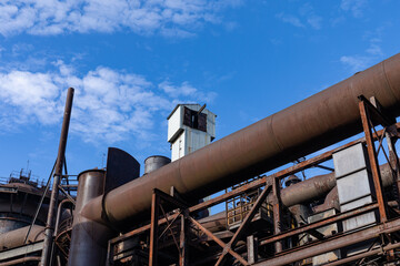 Rusting metal exterior of an old industrial site against a brilliant blue sky, industrial landscape, horizontal aspect