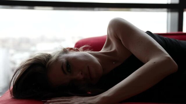 beautiful woman is moving erotically for camera, flirting and posing on sofa, playful look