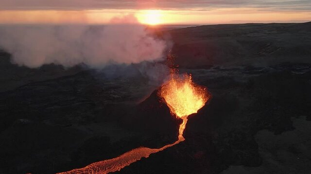Fountain of magma and lapilli erupting from volcano crater at sunset, Iceland. Aerial static