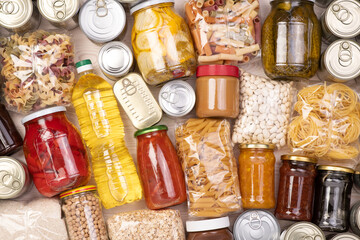 Lebensmittelspenden wie Nudeln, Reis, Öl, Erdnussbutter, Konserven, Marmelade und andere auf weißem Holztisch, Draufsicht