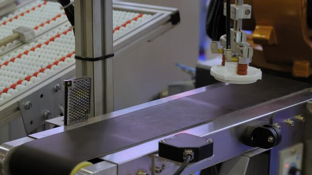 Pick and place robotic arm manipulator moving plastic detail on conveyor belt at modern robot trade show, exhibition - close up. Manufacturing, engineering, industrial, automated technology concept