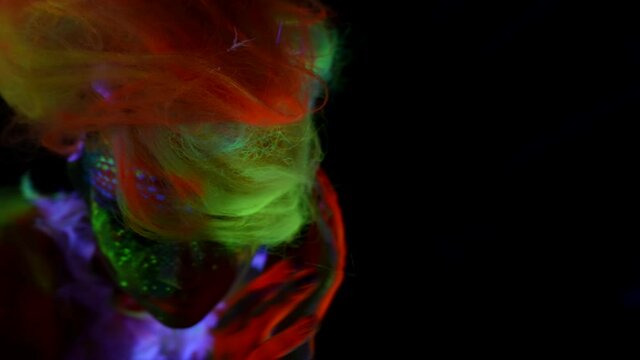 young lady with neon dyes on skin of face and body and extravagant hairstyle
