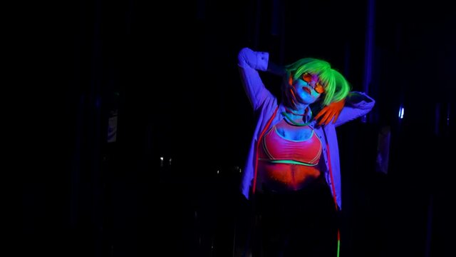go-go dancer woman is moving in nightclub, fluorescent makeup and wig in UV lights on dance floor