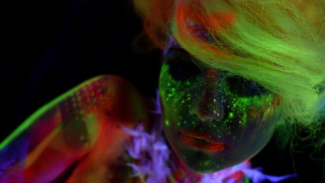 amazing beautiful woman with fluorescent makeup and body art, closeup shot of face, UV light