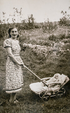 Germany - CIRCA 1930s: Portrait of mother and baby in carriage. Young female and baby in stroller pram. Vintage historical archive photo
