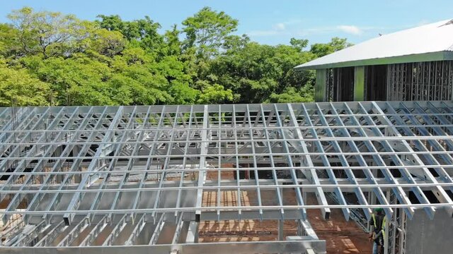 Metal roof structure, structural framing steel studs in green remote residential construction site project. Eco built architectural engineering framework design. Modern aerial perspective and geometry