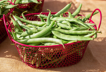 Green beans in red wire baskets, close up, farmers market