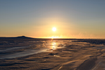 Fototapeta na wymiar Arctic landscape in winter time. Small river with ice in tundra. Sunset.