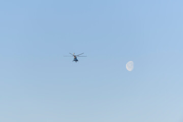 Helicopter flying in the blue sky with moon.