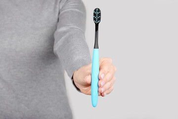 Hand with dental toothbrush on grey background