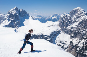 Fototapeta na wymiar slender positive smiling girl climber mountaineer on a snowy alpine slope