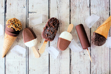 Assorted chocolate ice cream desserts. Above view scattered on a rustic white wood background.