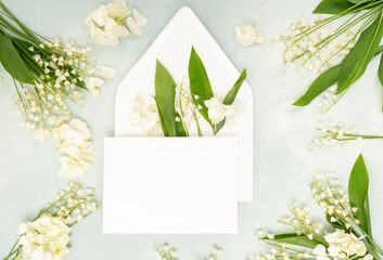 Bridal stationery flat lay with envelope and card and fresh lily of the valley flowers