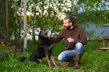A happy man is giving his pet pal a verbal reward. The man is petting his dog on the head and scratching him behind his ears to show him approving of his behaviour