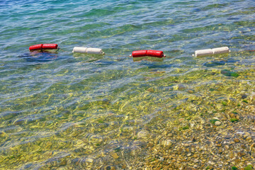 Sunny summer day. Shallow water, string of red and white buoys on water. Beach vacation concept