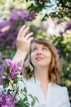 Candid Authentic Portrait Of 30s 40s Caucasian Blonde Woman With Lilac Flowers. 30 40 Year Old Woman Enjoying Life In Lilac Flowers Nature Background. Reinvention, Life Changes, Reinvent Yourself