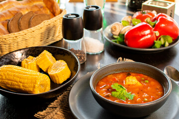 Mexican tomato, bean, bell pepper soup and corn in the dark bowl.