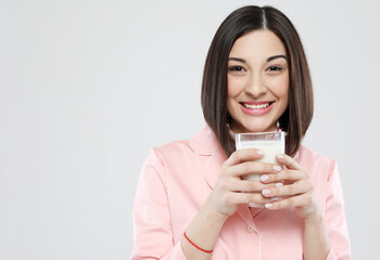 lifestyle, health and people concept: beautiful asian female dressed in pink pajamas holding a glass of milk
