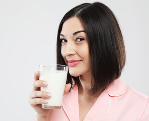 lifestyle, health and people concept: beautiful asian female dressed in pink pajamas holding a glass of milk