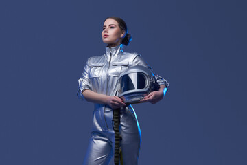 Young spacewoman in silver suit holding helmet